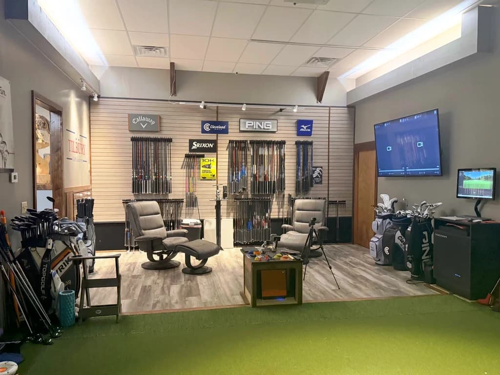 The fitting studio: a shaft wall from Callaway, Cleveland, Srixon, PING, and Mizuno, with lounge chairs and a TrackMan station