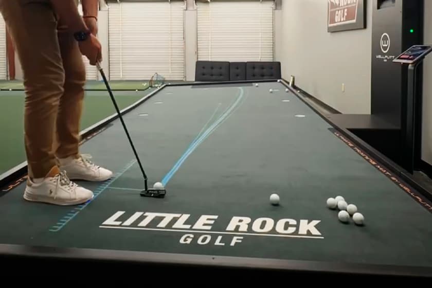 A golfer putting along a projected laser line on a BigTilt platform